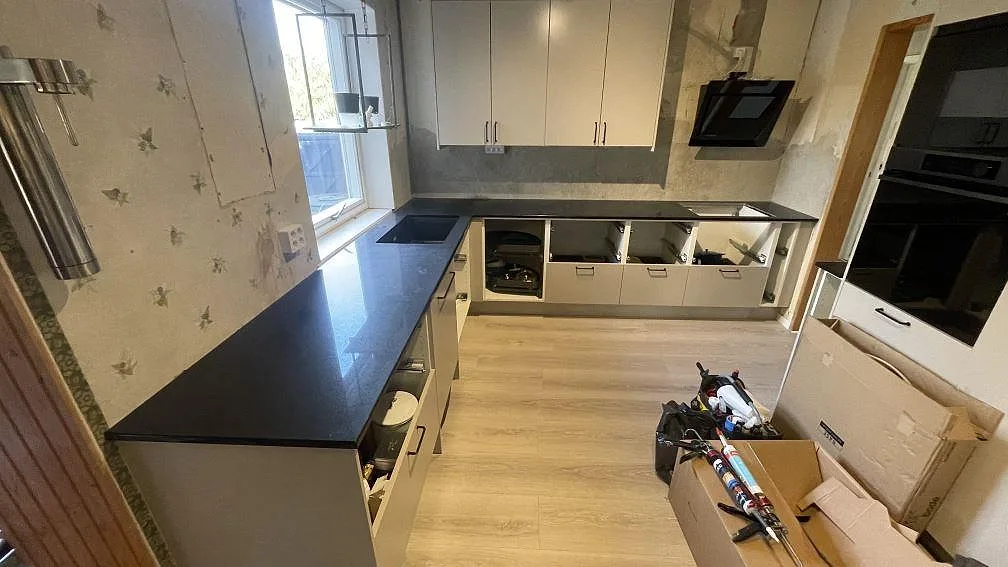 Köksbänkskivor i svart Technistone Gobi Black kvartskomposit, 20 mm polerad, på ljusa köksstommar under montering i Ystad.