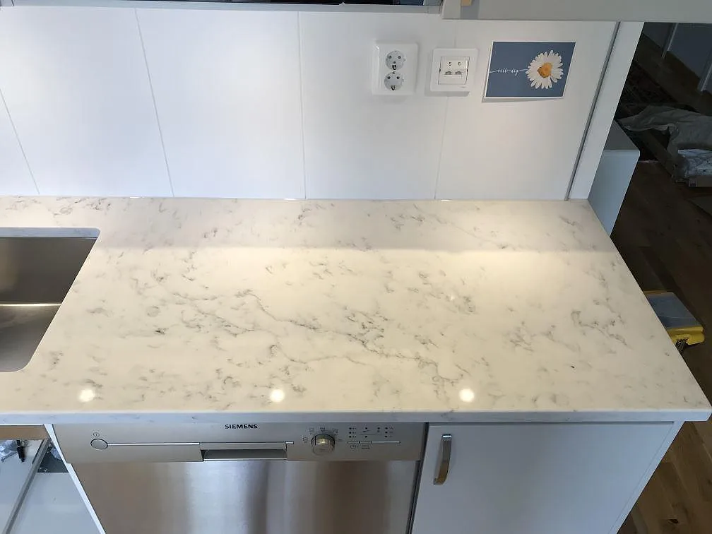 Polerad köksbänkskiva i Technistone Mystery White i Åhus med underlimmad rostfri diskho och Siemens-diskmaskin under bänken.