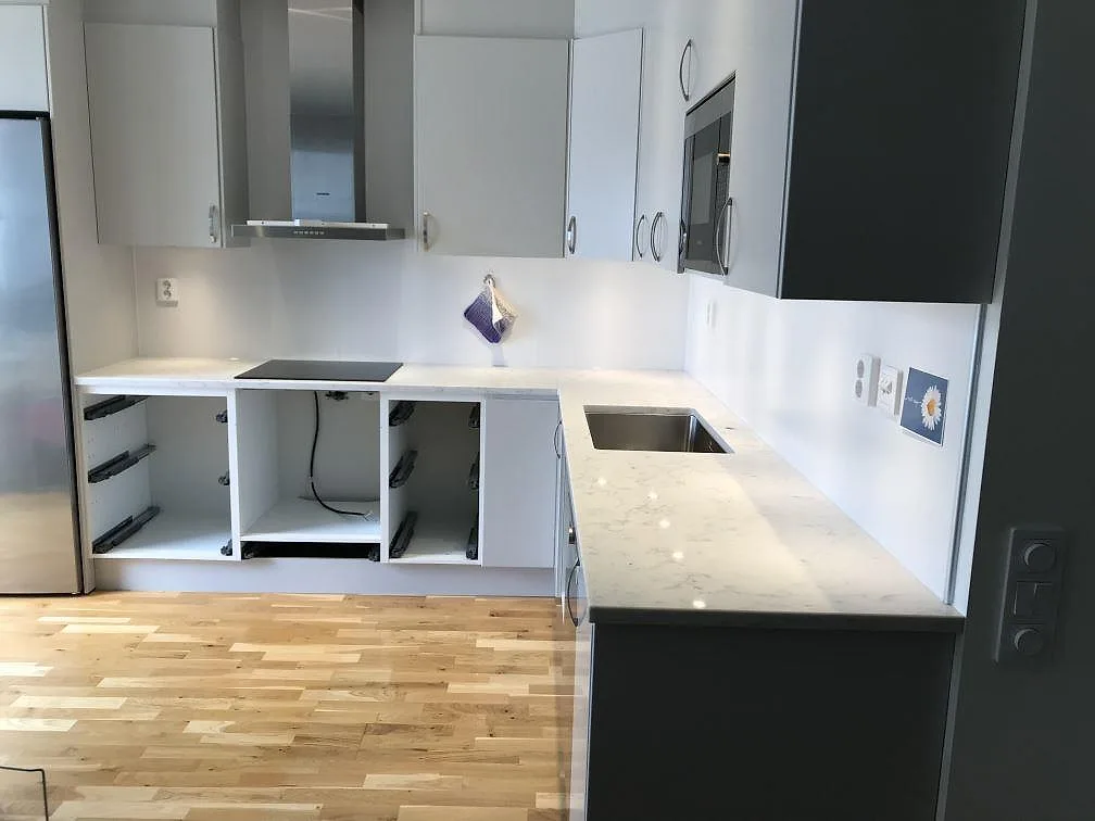 Köksbänkskiva i vit Technistone Mystery White, polerad, i ett U-format kök i Åhus med infälld induktionshäll och underlimmad diskho, fotograferat under montering.