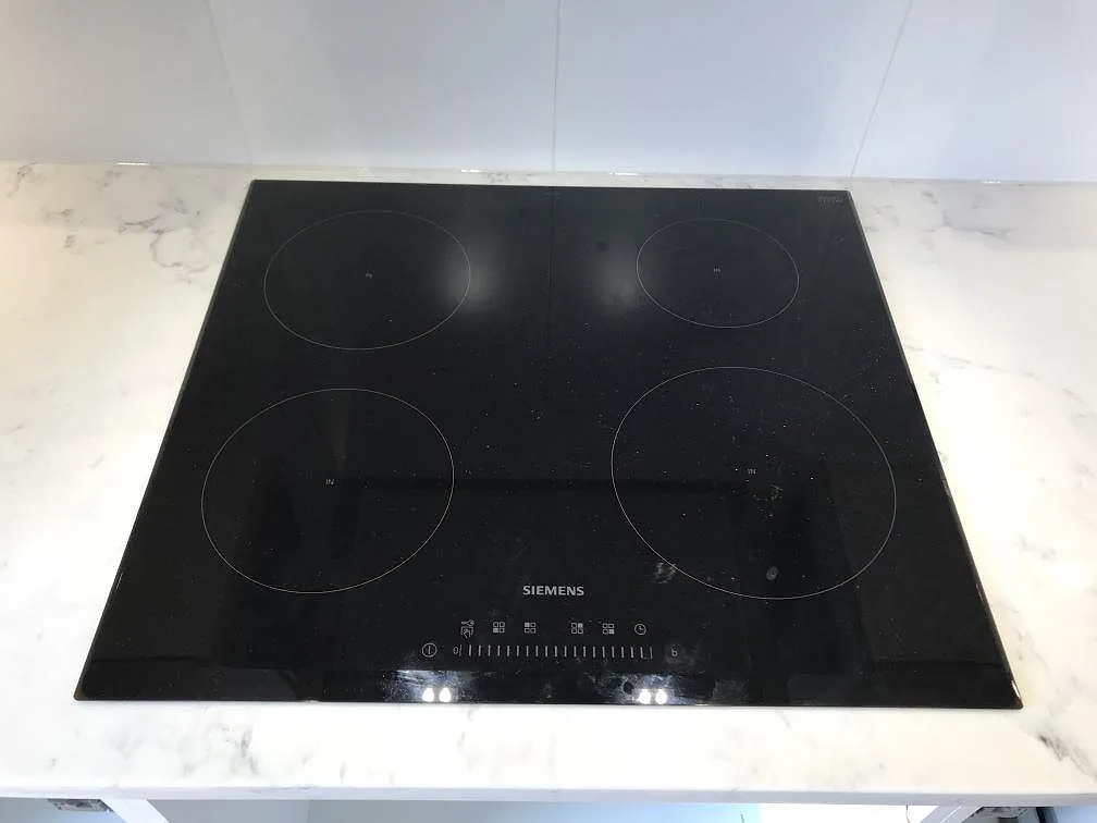 Infälld Siemens induktionshäll med fyra zoner i en polerad köksbänkskiva av Technistone Mystery White i Åhus.