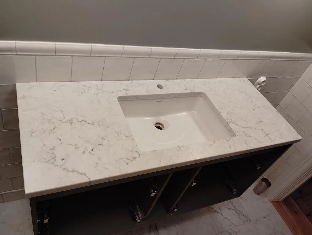 Badrumsbänkskiva i vit Technistone Mystery White, polerad komposit, med vitt tvättställ och grå ådring i Älvsjö.