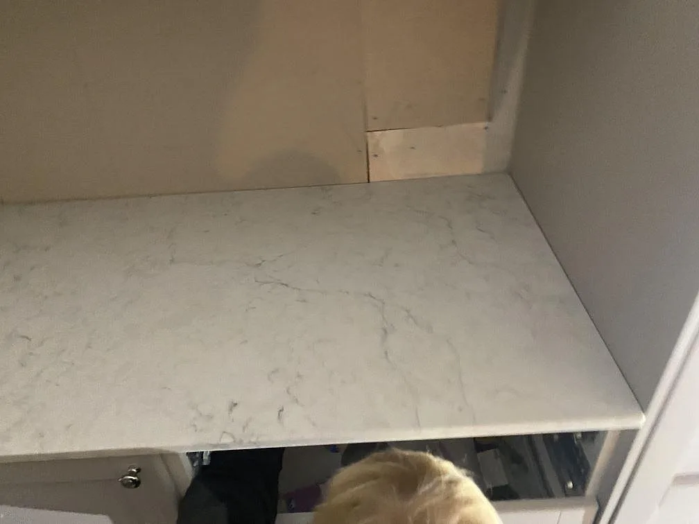Köksbänkskiva i polerad Technistone Mystery White monterad mot vägg med öppna lådstommar under arbetet i Alingsås.