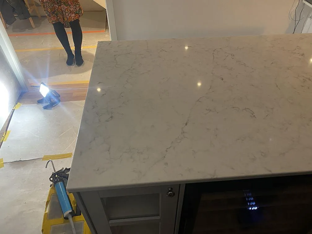 Polerad köksö i Technistone Mystery White med blandarhål och spegelblank yta i ett kök under montering i Alingsås.