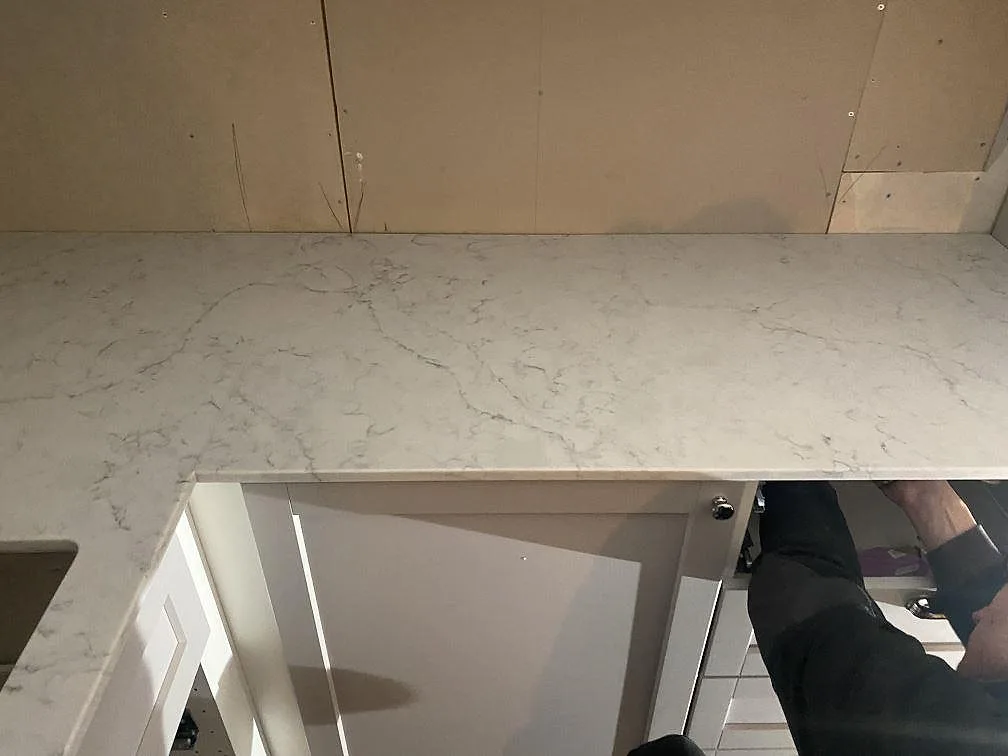 Polerad köksbänkskiva i Technistone Mystery White med mjuk grå ådring längs väggen i ett kök i Alingsås.