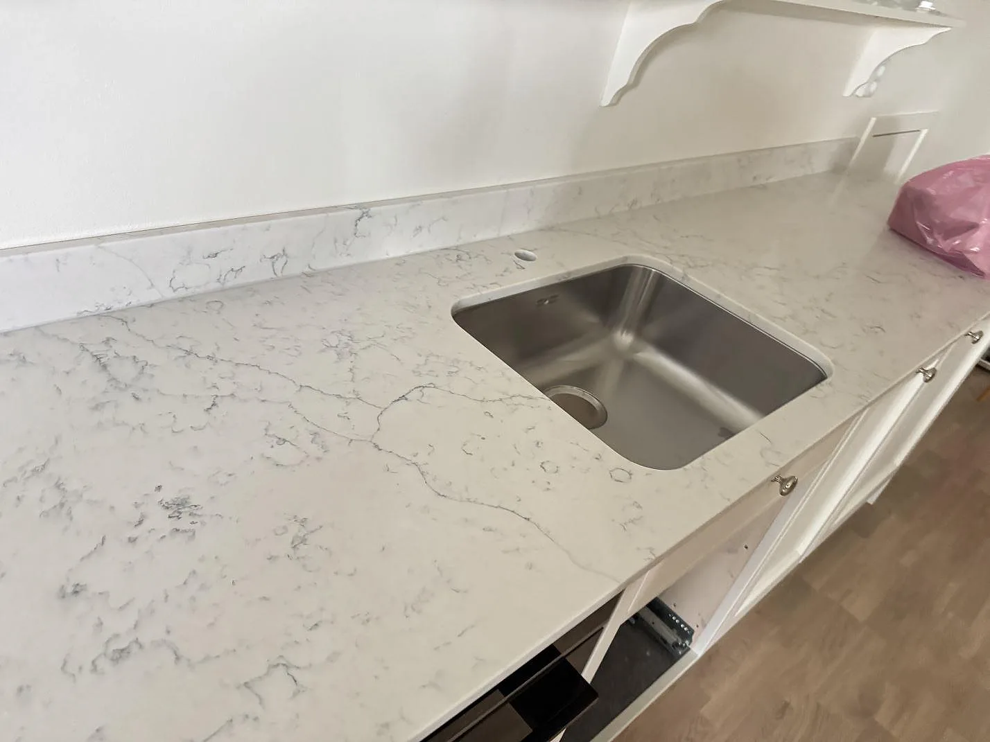 Polerad Technistone Mystery White köksbänk med rostfri diskho, blandarhål och låg stänkkant längs väggen i Barsebäck.