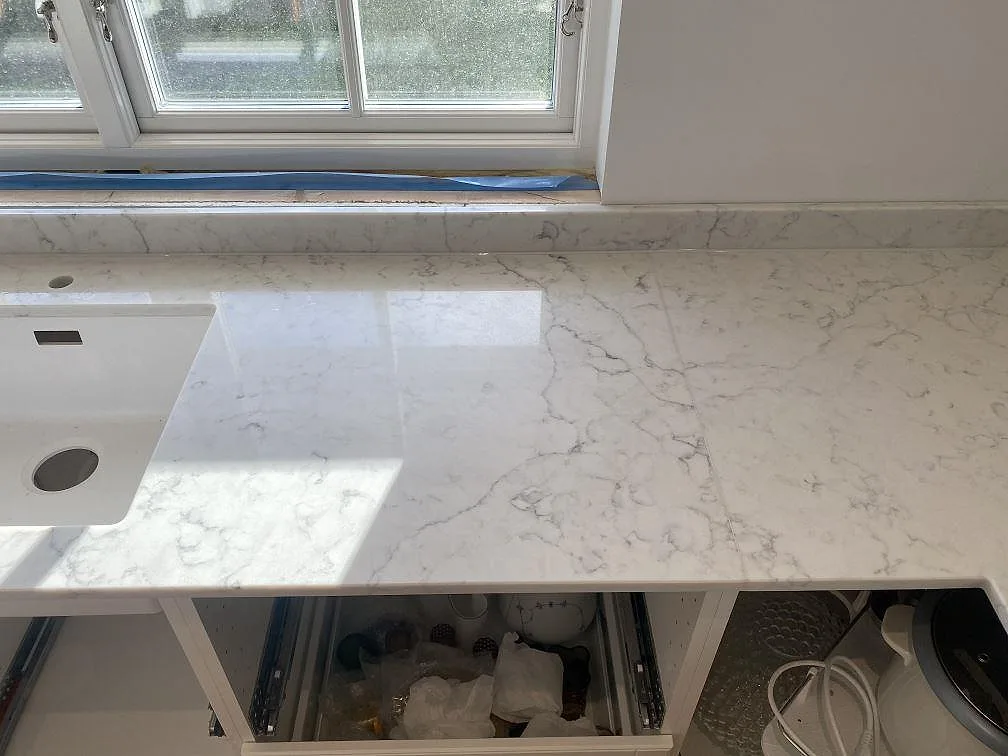 Köksbänkskiva i vit Technistone Mystery White komposit vid fönster med en vit underlimmad diskho och avtorkningsyta i Bjärred.