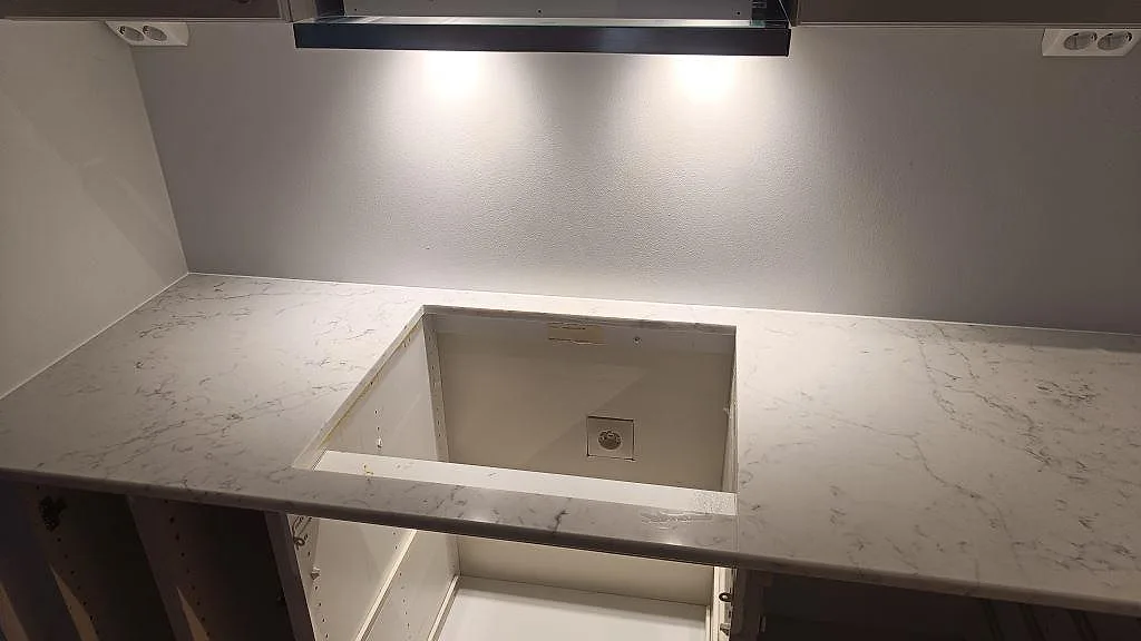 Hällurtag i köksbänkskiva av polerad Technistone Mystery White under fläktkåpa i ett kök i Bjärred.