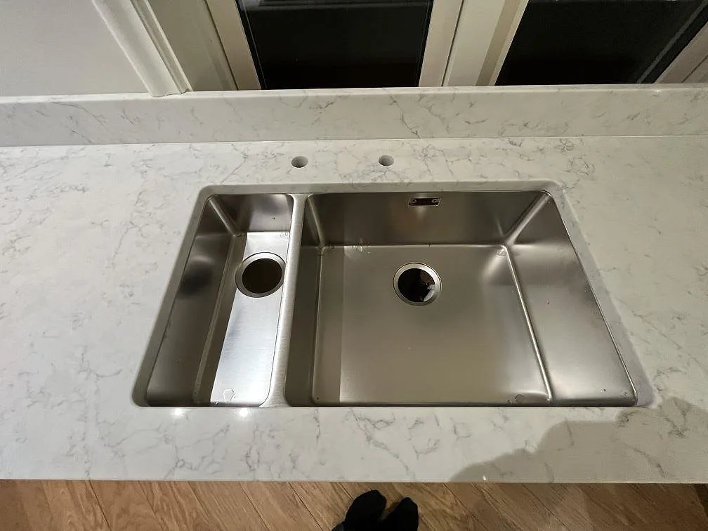 Dubbel underlimmad rostfri diskho i en polerad Technistone Mystery White köksbänkskiva med uppvikt stänkkant i Bromma.