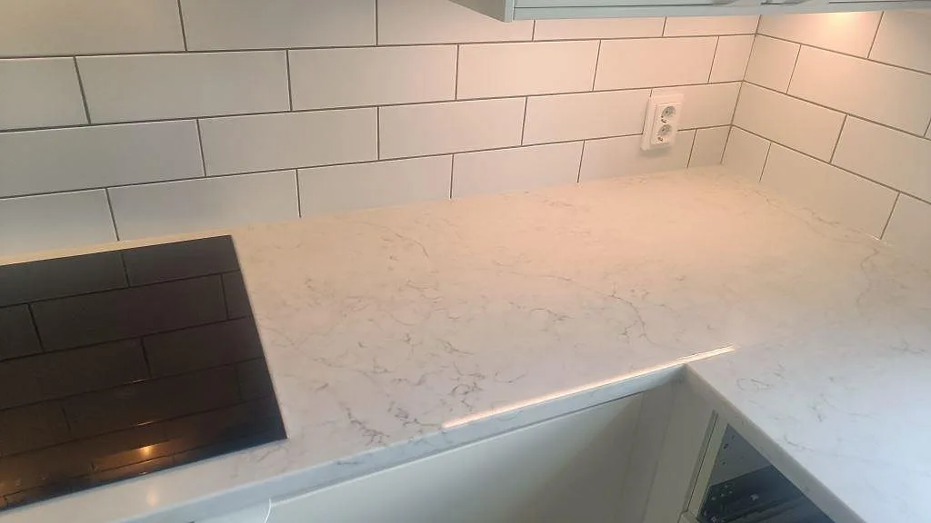 Arbetsyta i polerad Technistone Mystery White vid svart häll och vitt kakel i köket i Bunkeflostrand.