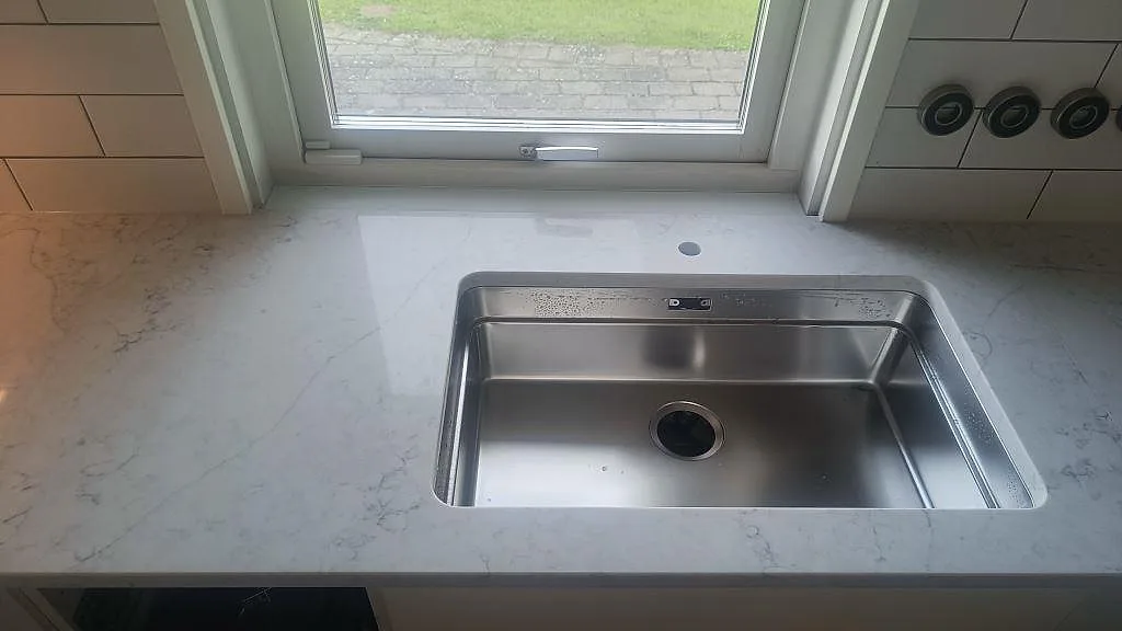 Underlimmad rostfri diskho i en polerad Technistone Mystery White bänkskiva vid fönster i köket i Bunkeflostrand.