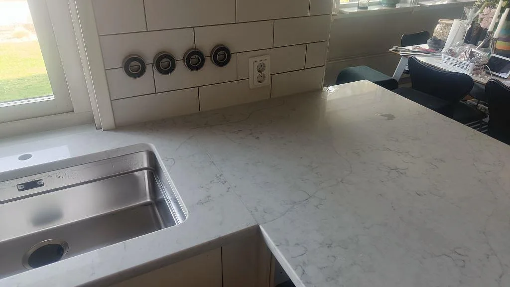 Polerad Technistone Mystery White runt diskho och arbetsyta vid fönster, med vitt kakel i kök i Bunkeflostrand.