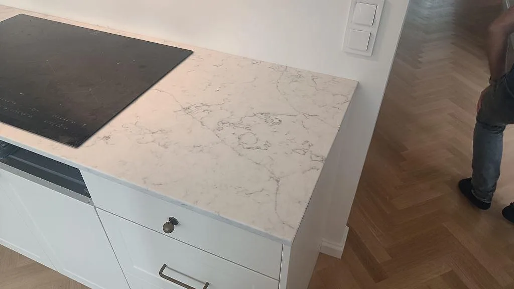 Sidovy av polerad Technistone Mystery White vid hällzon, med ådrad 20 mm kvartskomposit på vitt kök i Bunkeflostrand.