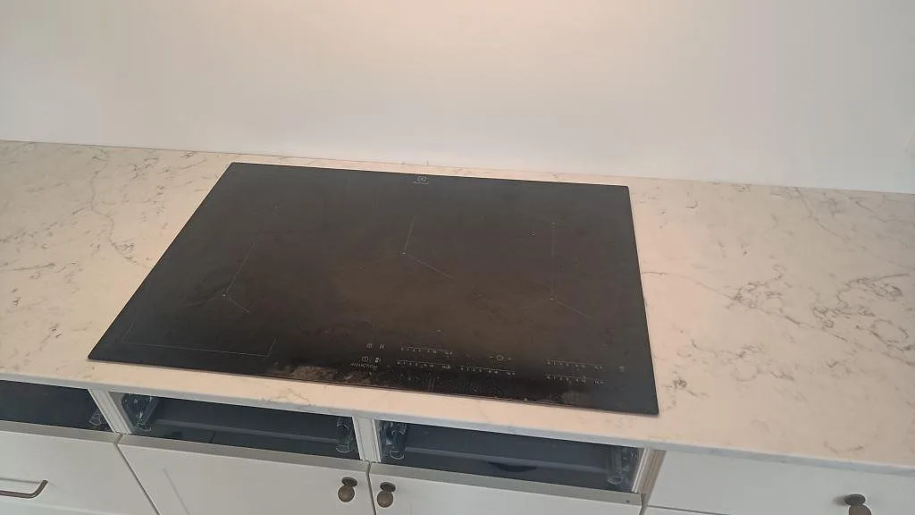 Detalj av hällzon i polerad Technistone Mystery White, 20 mm kvartskomposit, monterad på vita köksskåp i Bunkeflostrand.