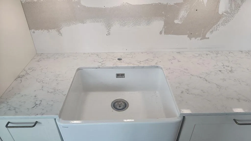 Närbild på polerad Technistone Mystery White i kök i Bunkeflostrand, med ljus grå ådring runt den synliga diskhozonen.