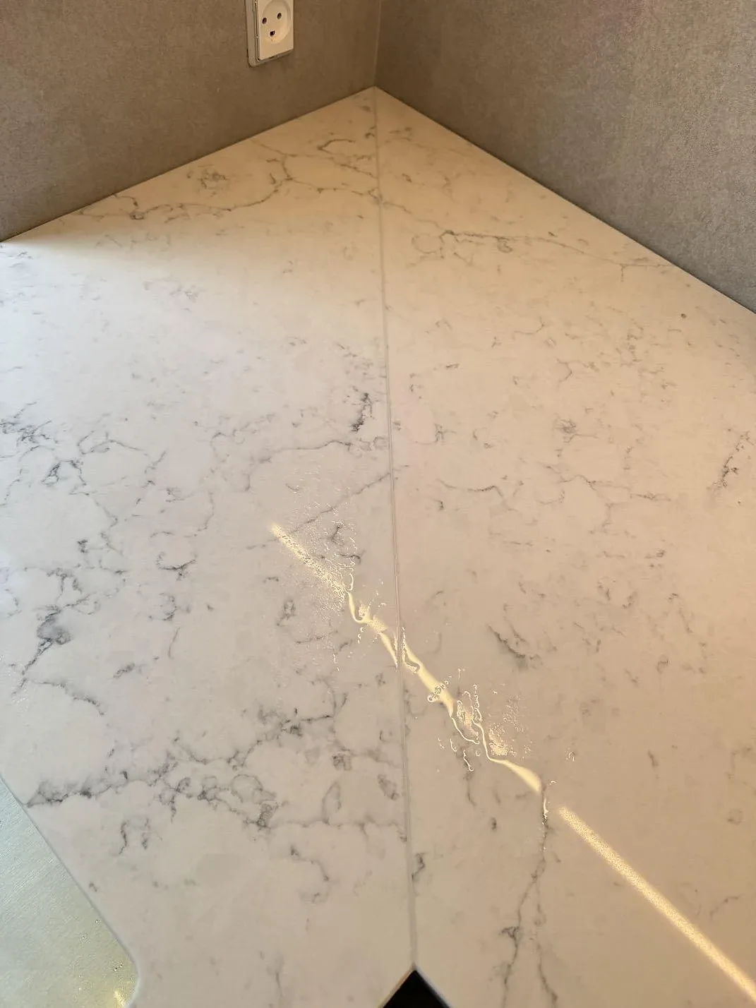 Topvy över hörn och skarv i polerad Technistone Mystery White, vit kvartskomposit med grå marmorådring i Charlottenlund.