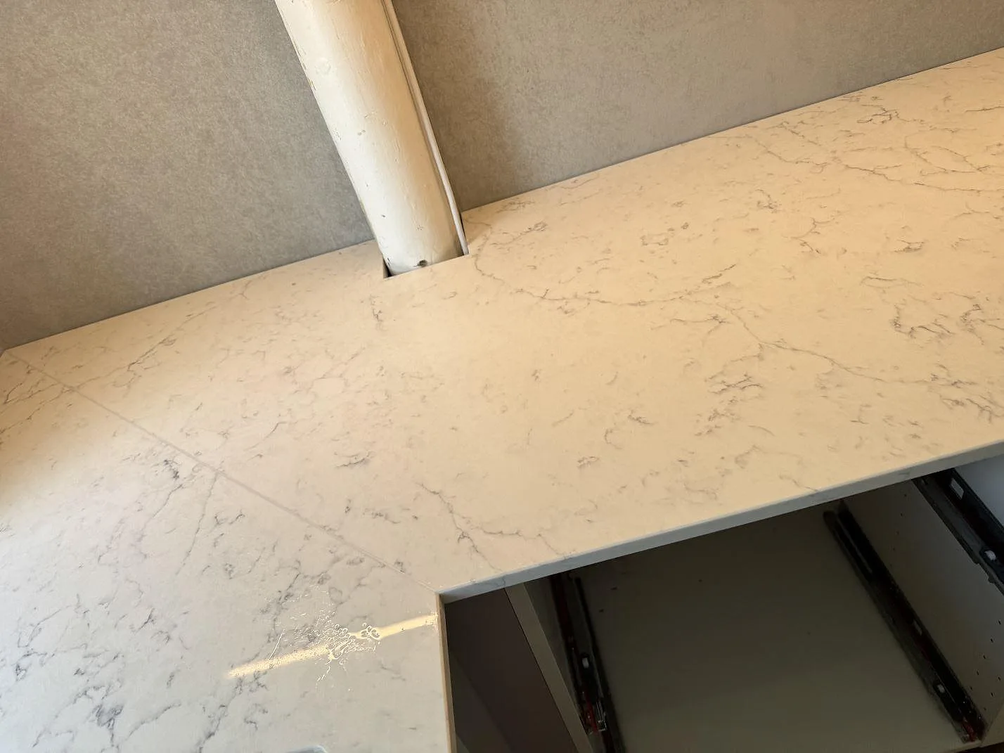 Rak arbetsyta i polerad Technistone Mystery White med urtag kring väggdetalj och öppna stommar i ett kök i Charlottenlund.