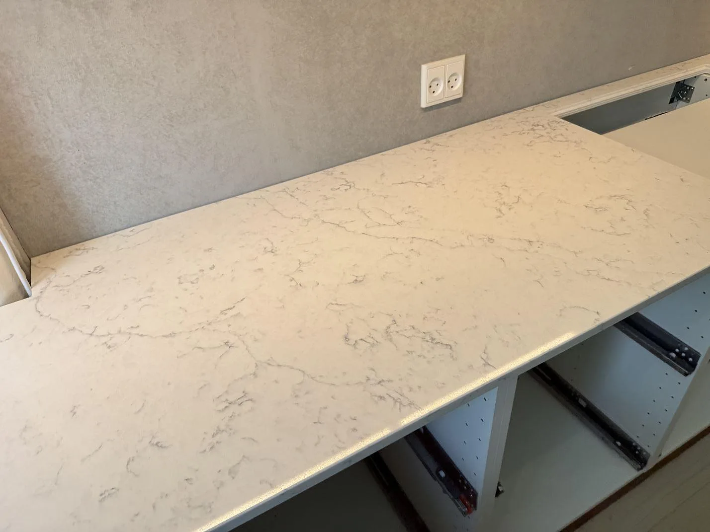 Lång köksbänk i vit Technistone Mystery White kvartskomposit med polerad yta över öppna köksstommar i Charlottenlund.