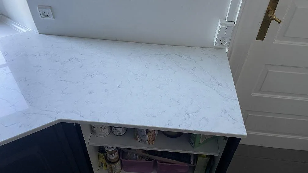 Sidoyta i vit Technistone Mystery White köksbänkskiva, polerad, monterad intill dörr och öppna stommar i Copenhagen.