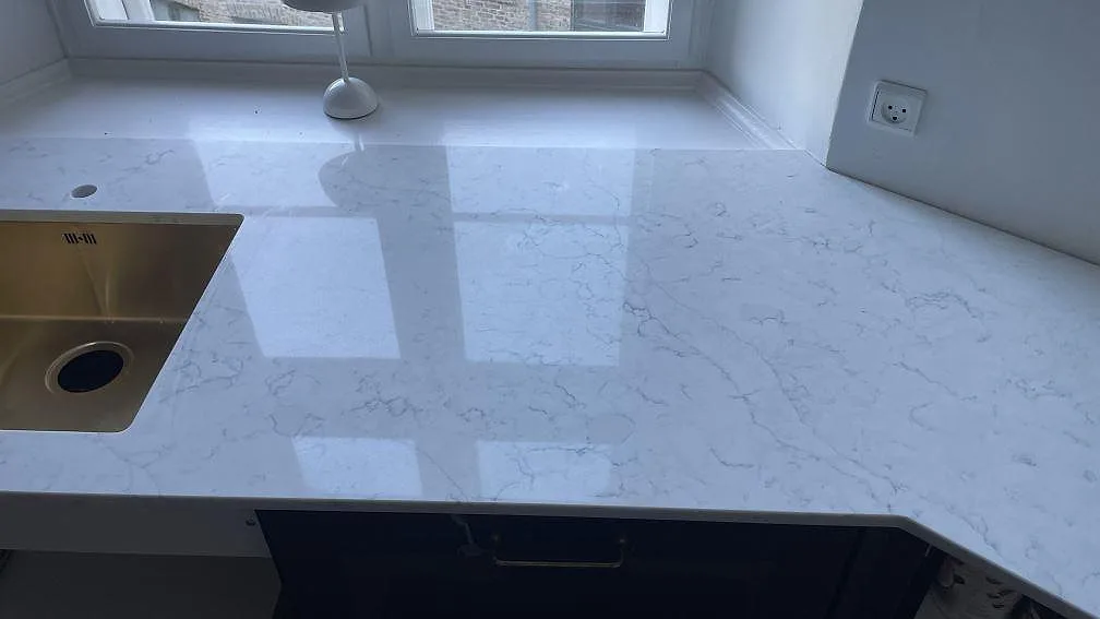 Polerad köksbänkskiva i Technistone Mystery White vid fönster, med blank yta och ljusgrå ådring i Copenhagen.