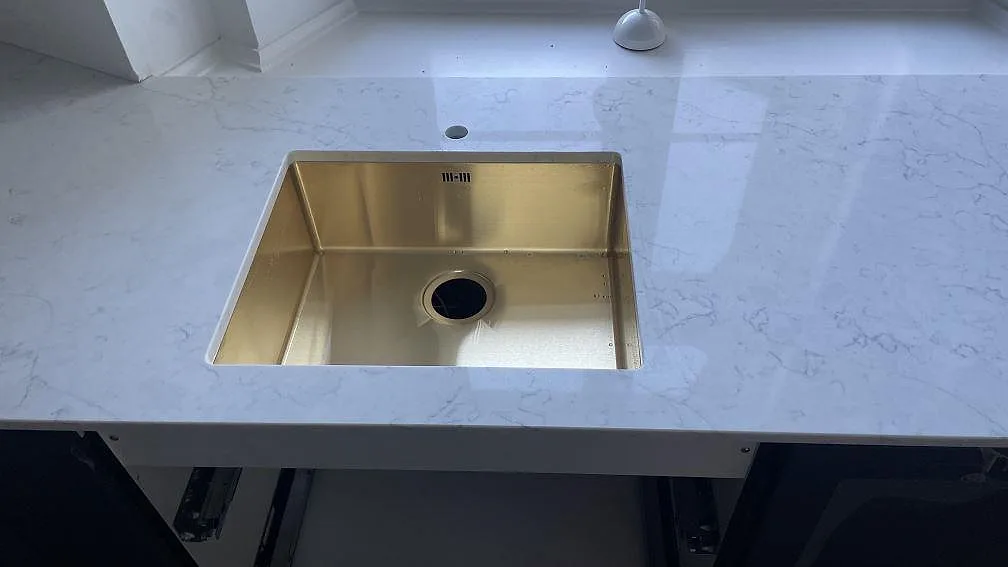 Närbild på polerad Technistone Mystery White köksbänkskiva med synlig diskho och grå ådring i Copenhagen.