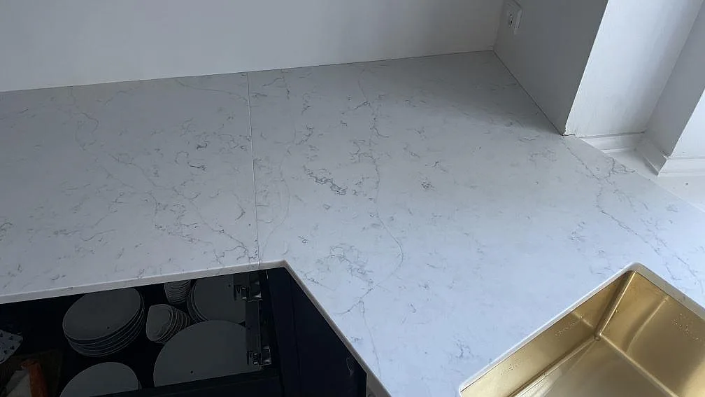 Hörnparti av köksbänkskiva i Technistone Mystery White kvartskomposit, polerad, med diskho i kanten i Copenhagen.