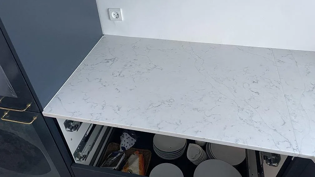 Rak arbetsyta i polerad Technistone Mystery White över mörka köksskåp, med diskret skarv och grå ådring i Copenhagen.