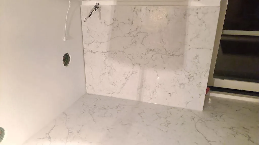 Detalj av Technistone Mystery White som bänkskiva och stänkskydd i ett våtutrymme under montering i Falsterbo.