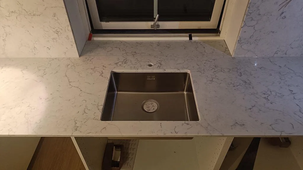 Närbild av polerad Technistone Mystery White som bänkskiva med rektangulärt urtag och grå ådring i Falsterbo.