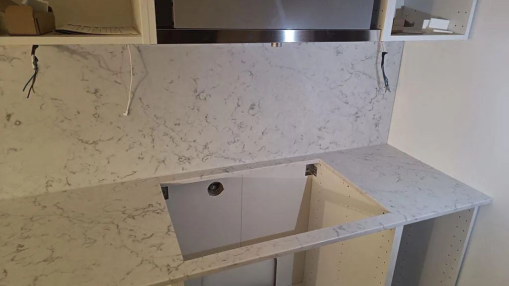 Bänkskiva i Technistone Mystery White med matchande stänkskydd och urtag i ett våtutrymme under montering i Falsterbo.