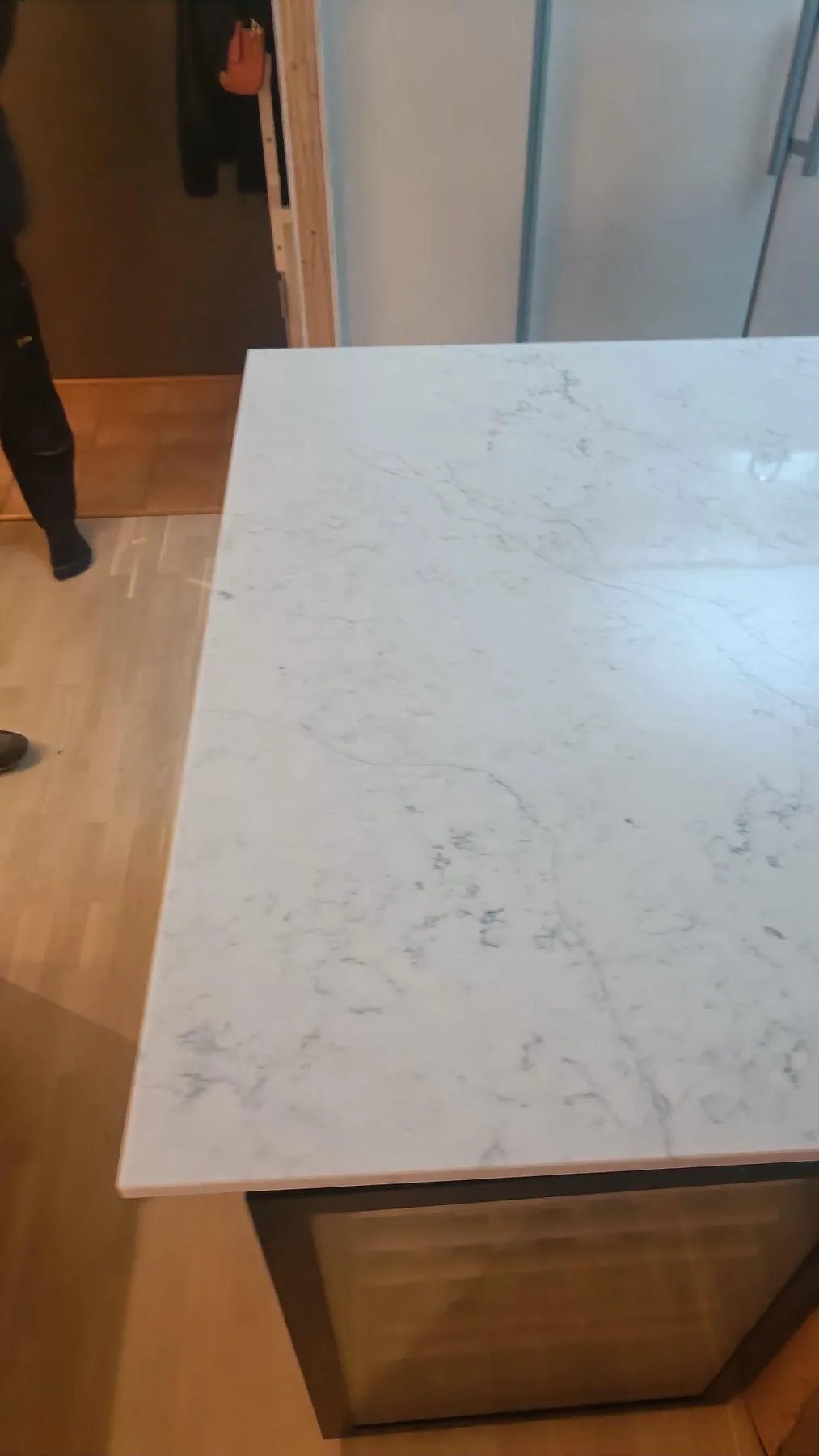 Kantdetalj på polerad köksö i Technistone Mystery White komposit med ljus ådring under montering i Göteborg.