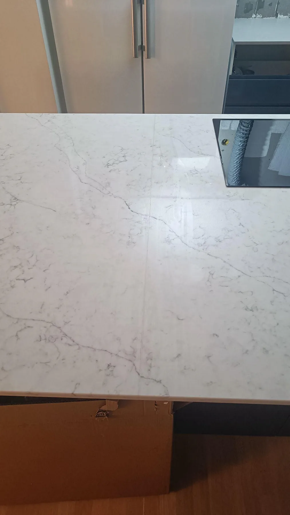 Detalj av ljusgrå ådring och skarv i polerad Technistone Mystery White kvartskomposit på köksö i Göteborg.