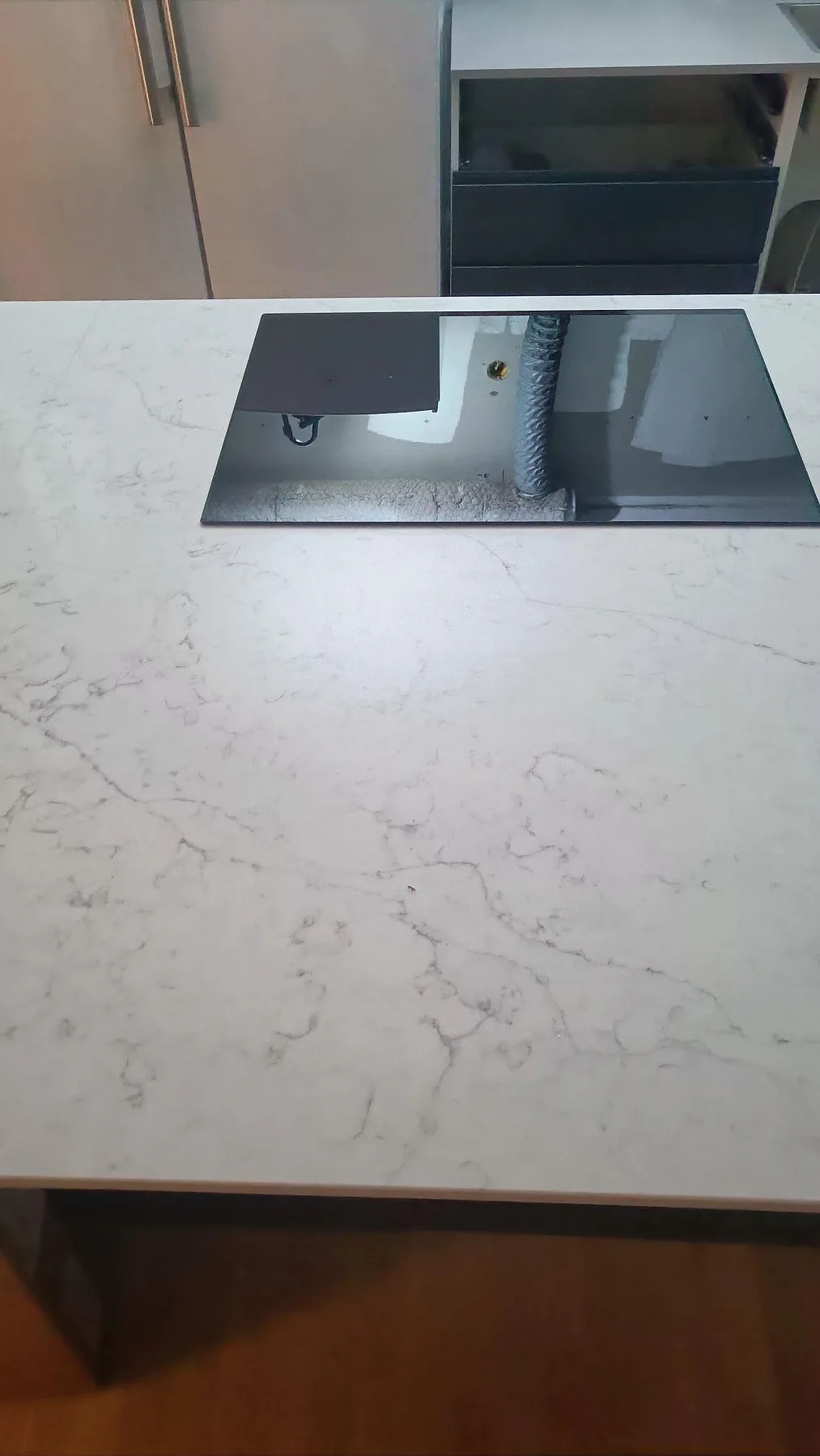 Närbild av svart häll och ljus ådring i polerad Technistone Mystery White bänkskiva i ett kök i Göteborg.