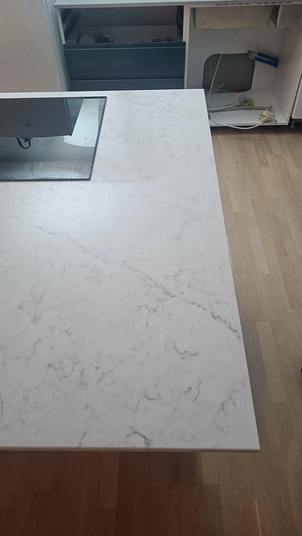 Polerad Technistone Mystery White köksö med häll och synliga köksstommar under montering i Göteborg.