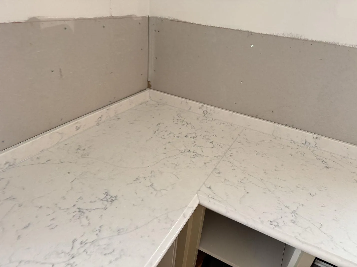 Hörnparti av polerad bänkskiva i Technistone Mystery White med tydlig grå ådring i ett kök i Habo.