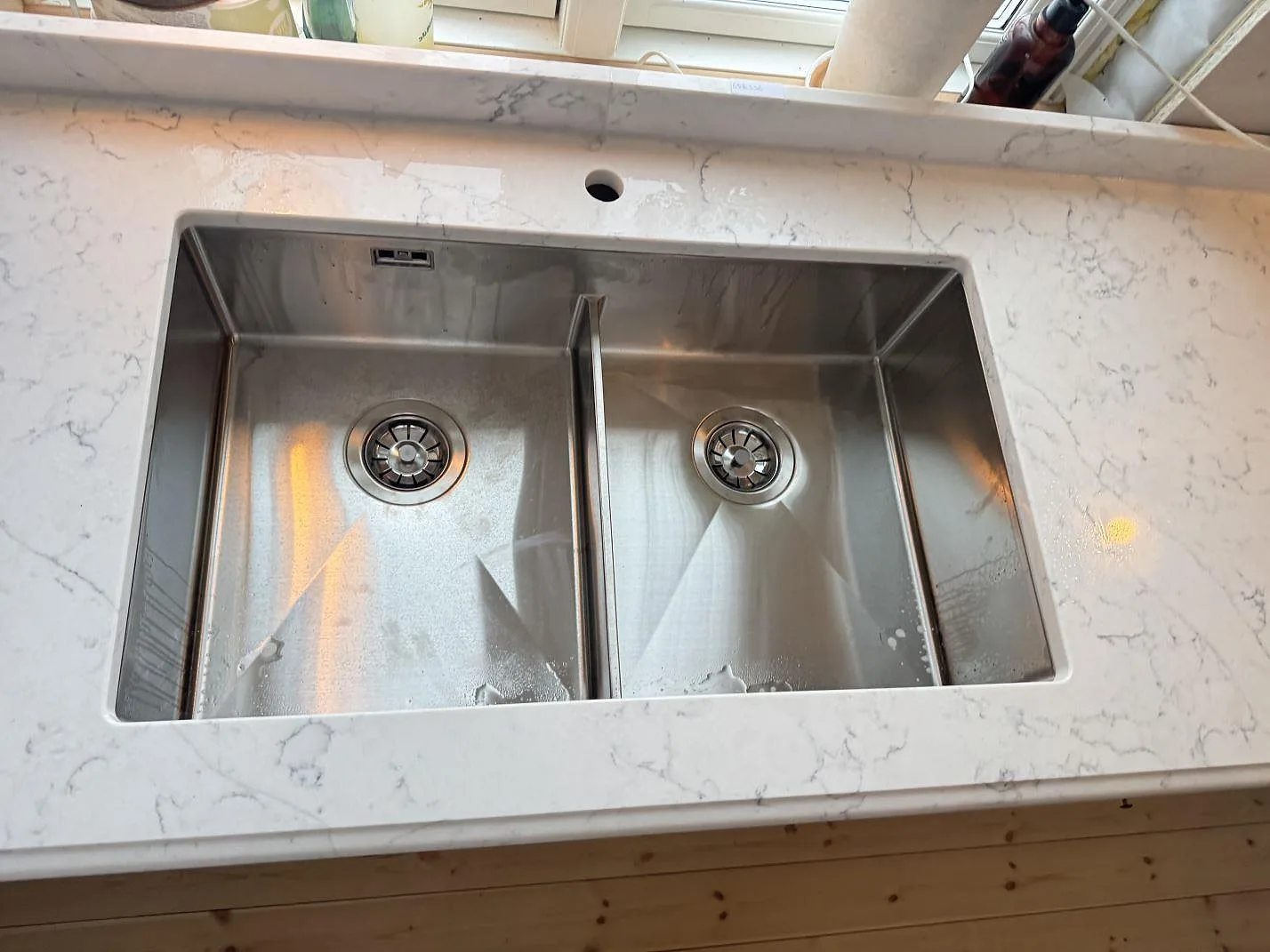 Underlimmad rostfri dubbelho infälld i polerad bänkskiva i Technistone Mystery White i ett kök i Habo.