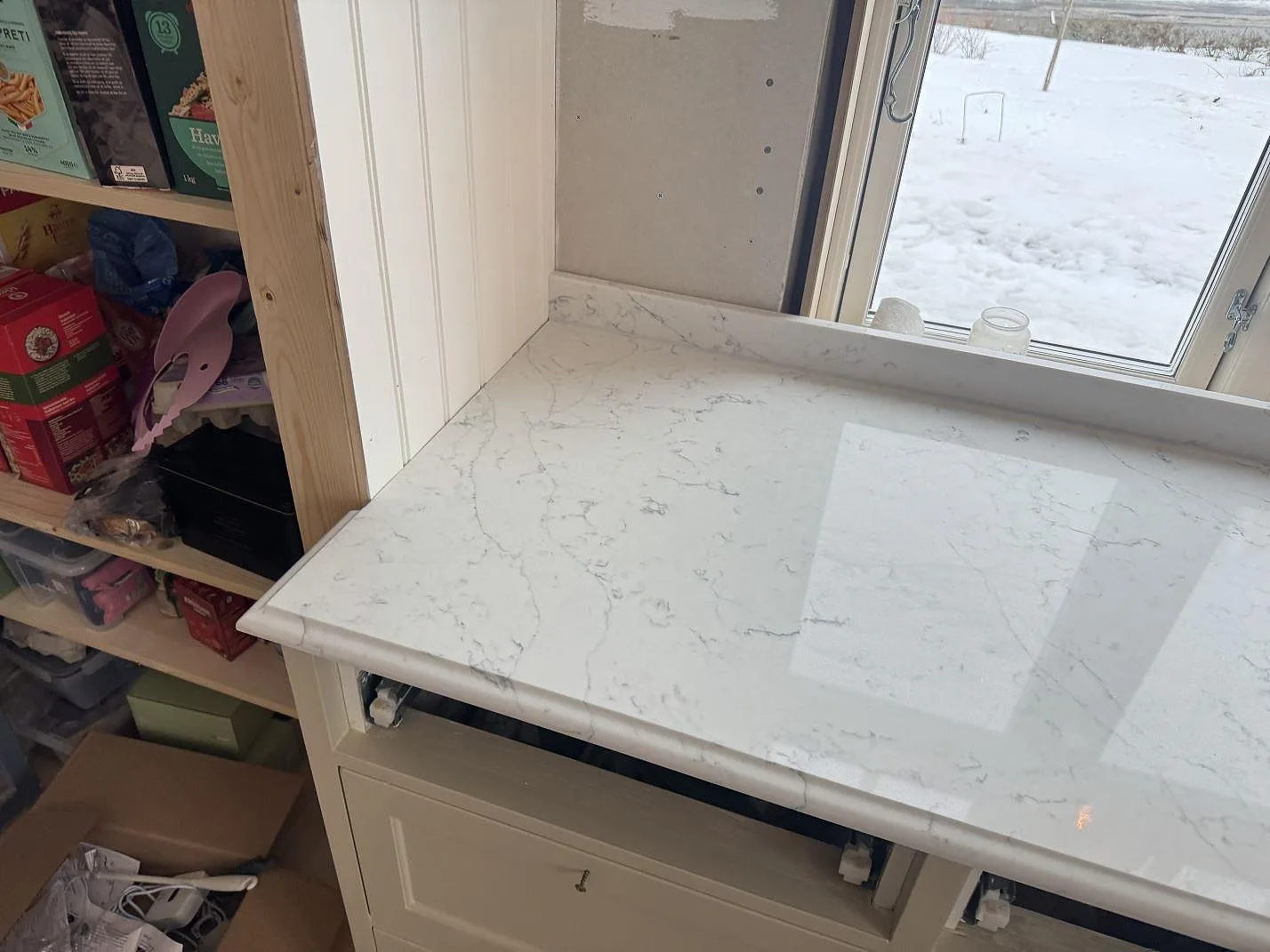 Bänkskiva i vit kvartskomposit Technistone Mystery White vid skafferiet med fönsterbänk i ett kök i Habo.