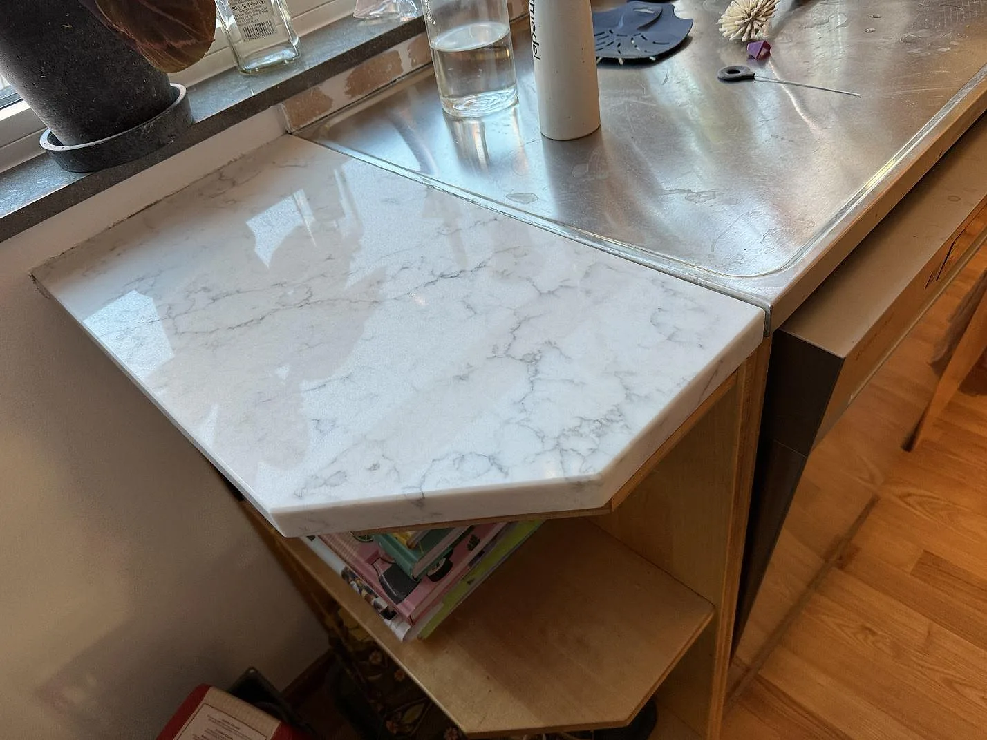 Polerad Technistone Mystery White komposit som bänkskiva intill rostfri diskbänk och fönster i ett kök i Hjärup.