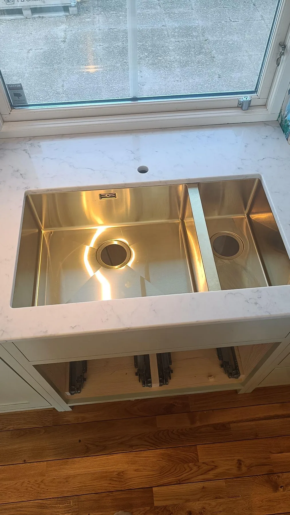 Underlimmad rostfri diskho monterad under en polerad bänkskiva i Technistone Mystery White i ett kök i Höllviken.