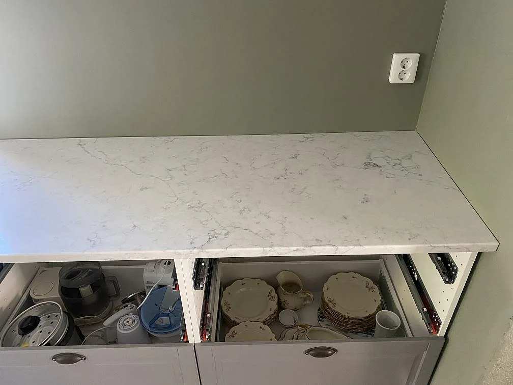 Köksbänkskiva i Technistone Mystery White mot grön vägg, polerad vit kvartskomposit med diskret ådring i ett kök i Klagstorp.