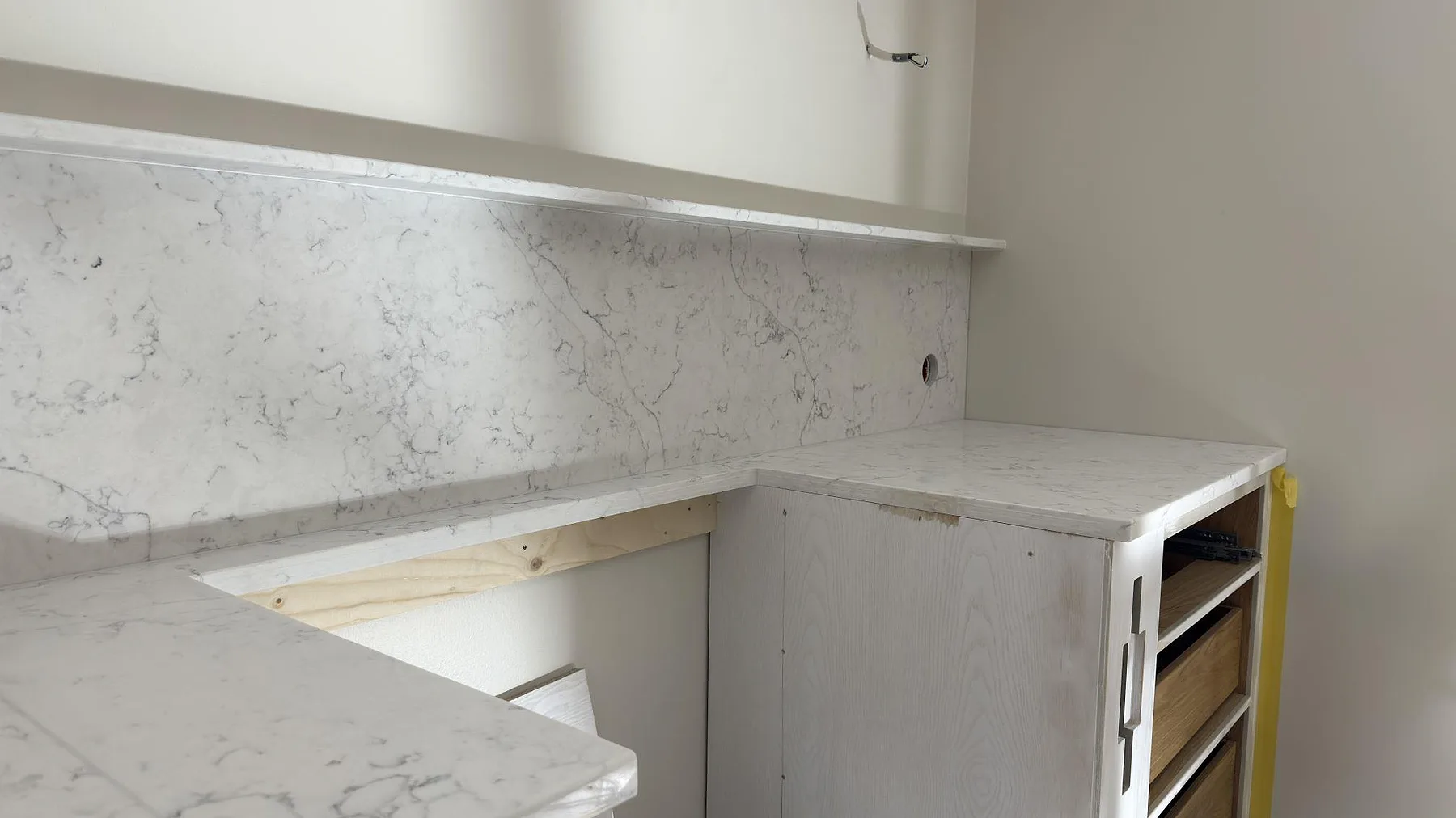 Hörnparti med köksbänkskiva, stänkskydd och förberett urtag i polerad Technistone Mystery White i ett kök i Lidingö.