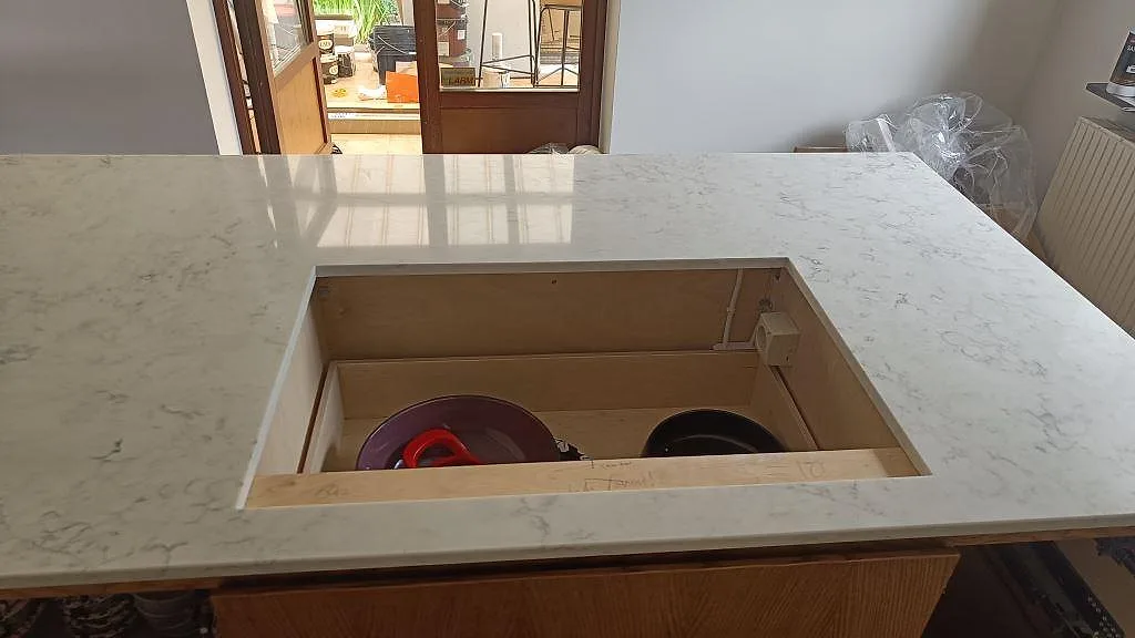 Detalj av polerad Technistone Mystery White runt ett öppet urtag i köksön under montering i Limhamn.