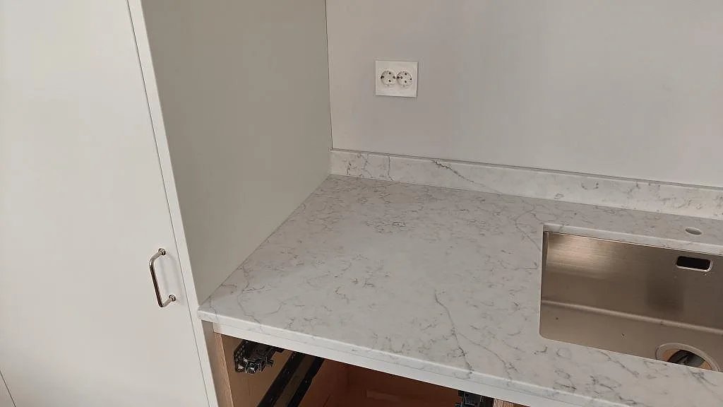 Diskhoavsnitt i polerad Technistone Mystery White med låg uppvikt stenkant och ljus grå ådring i Limhamn.