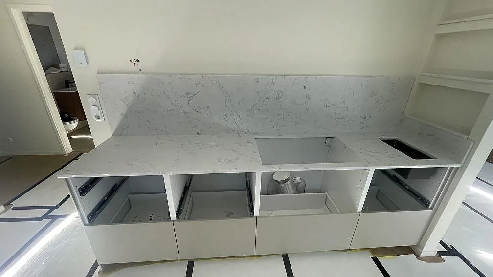 Polerad köksbänkskiva i Technistone Mystery White med uppvikt stänkskydd, hällöppning och diskho i Lomma.