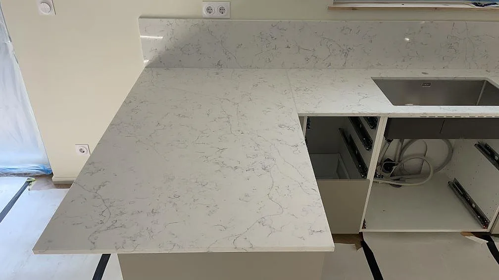 Stor bänkyta i polerad Technistone Mystery White komposit med ådring, stänkskydd och rostfri diskho i Lomma.