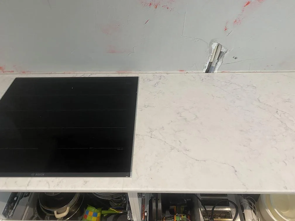 Köksbänk i vit Technistone Mystery White komposit med induktionshäll och borrat blandarhål, fotograferad innan köket var helt inrett i Lund.