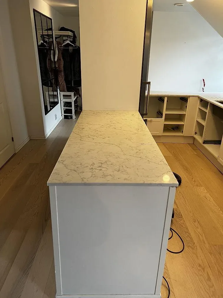 Köksö i vit Technistone Mystery White, polerad, fotograferad under montering i ett kök i Malmö med öppna stommar.