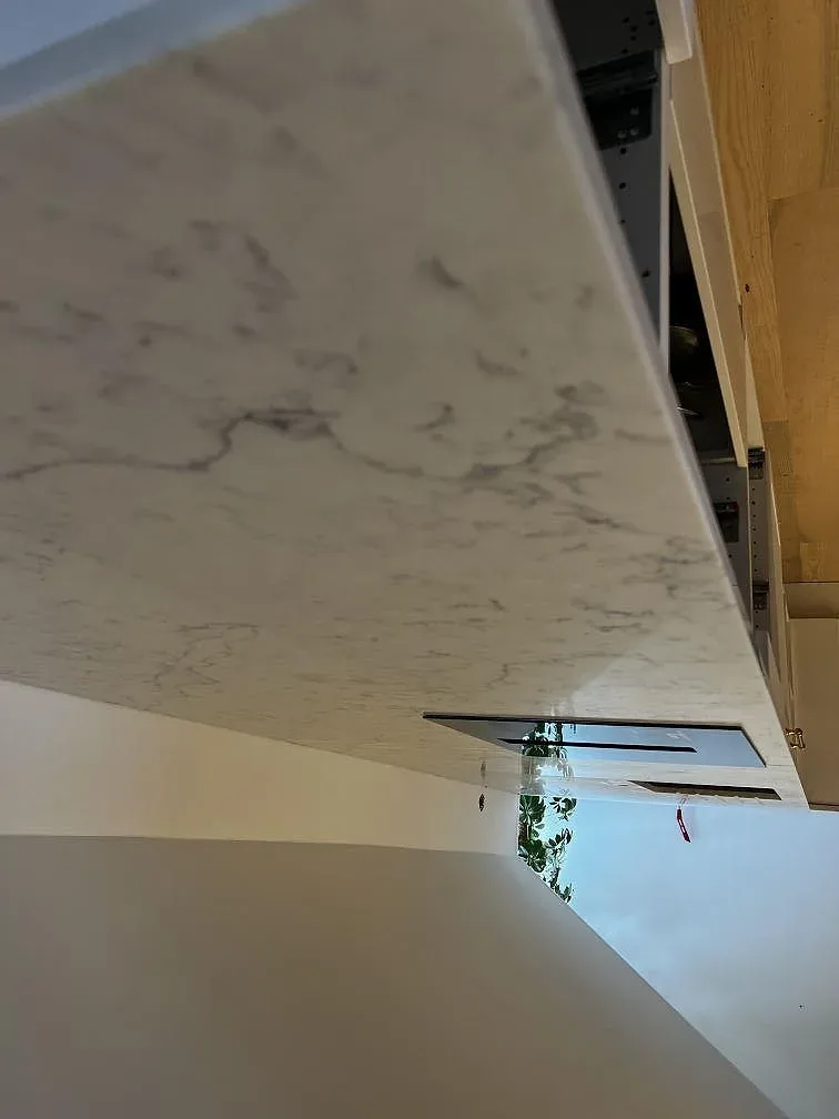 Köksbänkskiva i vit Technistone Mystery White med induktionshäll och grå ådring i ett kök i Malmö under montering.