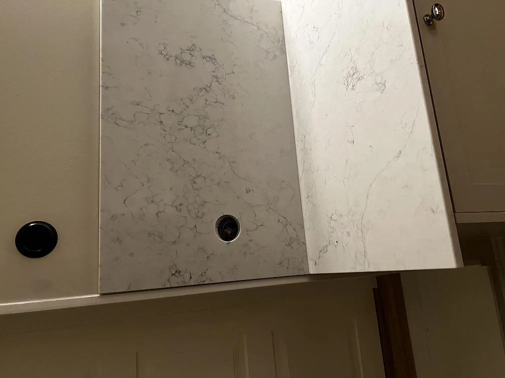 Detaljbild av ljus kompositbänkskiva i Technistone Mystery White med uppvikt stänkkant och rund genomföring i Malmö.