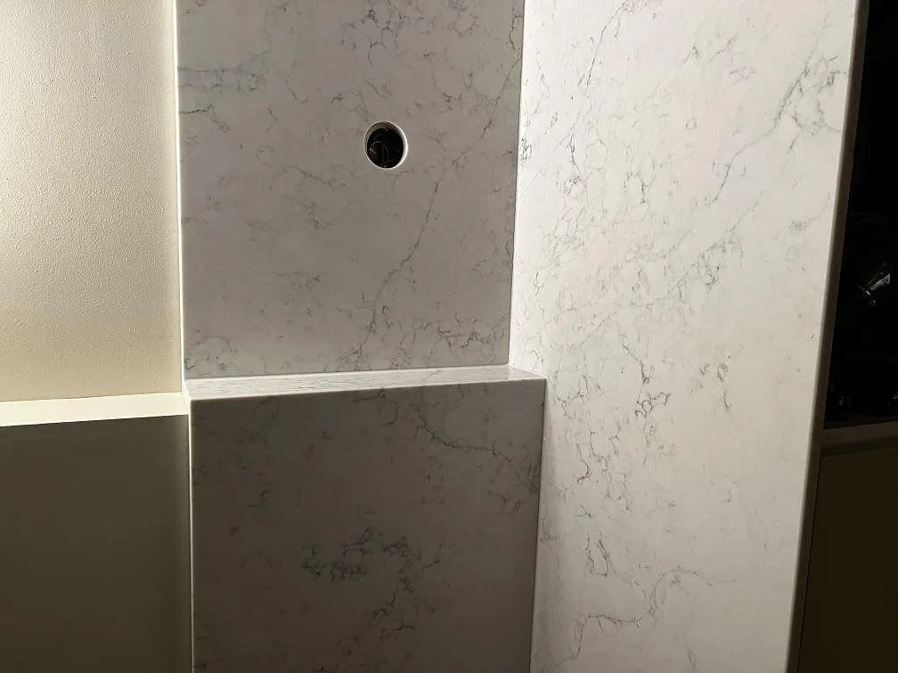 Närbild på stänkskydd och bänkskiva i Technistone Mystery White med grå ådring och polerad yta i Malmö.