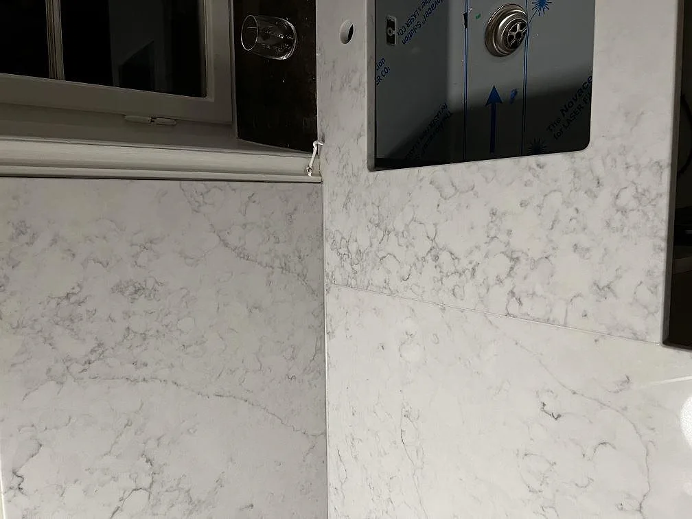 Närbild på Technistone Mystery White som bänkskiva och stänkskydd vid en svart underlimmad diskho under fönstret i Malmö.